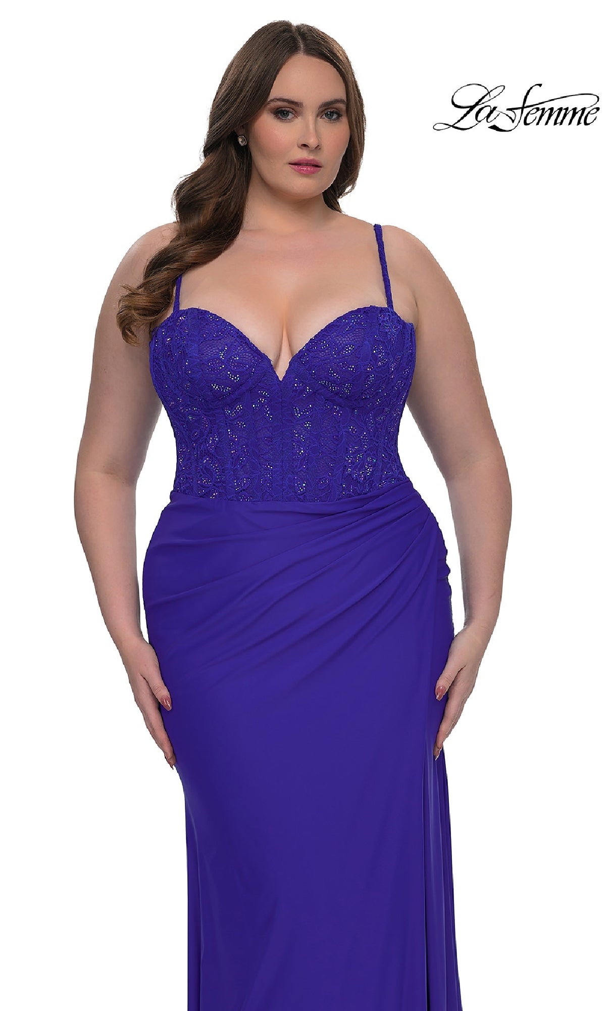 A woman models the Plus-Size Long Corset Prom Dress, La Femme 32449, in royal blue with a lace bodice and draped skirt, standing against a white background. The